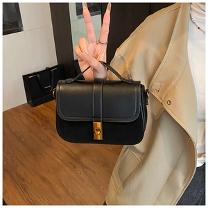 Detail view of black PU leather handbag with vintage gold twist lock and top handle