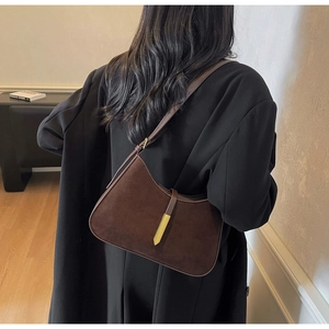 Detail der dunkelbraunen Wildleder-Hobo-Tasche mit Goldverschluss am Model