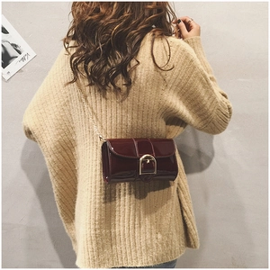 Détail du sac bandoulière en cuir verni bordeaux avec boucle fer à cheval et chaîne dorée