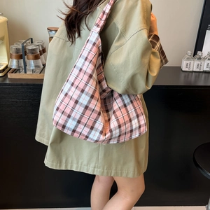 Sac fourre-tout en toile à carreaux roses porté par un mannequin dans un café chic