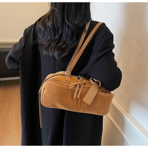 Detail view of brown suede bowling bag with tassels and hanging leather tag