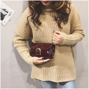 Détail du sac à main en cuir verni bordeaux avec boucle dorée et bandoulière chaîne