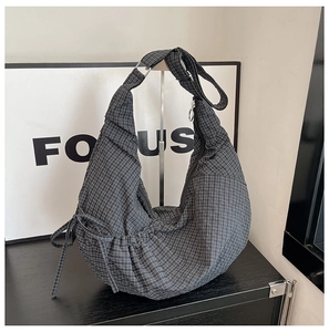 Detail of black and white checkered crescent bag with side drawstring and metal buckle