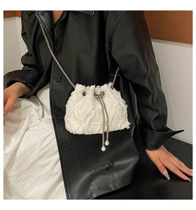Close-up of white drawstring bucket bag with silver chain and pearl pendant detail