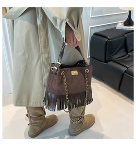 Close-up of brown suede tassel shoulder bag with diamond stitching and gold clasp
