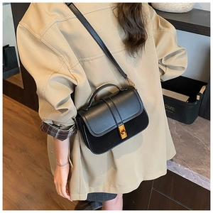Detail of minimalist black crossbody bag featuring matte leather and gold metal lock buckle