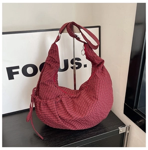 Detail of red checkered crescent shoulder bag with adjustable strap and side drawstrings