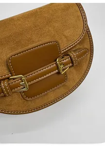 Detalle de bolso silla en ante marrón con hebilla dorada y costuras blancas
