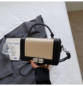 Detail of black and beige woven crossbody bag showing silver metal twist lock and top handle