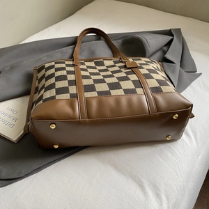 Detail of the checkered canvas tote bag showing golden protective metal feet and leather base