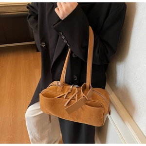 Detail of a brown suede bowling bag texture with zipper pocket and leather tag pendant