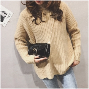 Détail d'un sac en cuir verni noir brillant avec bandoulière chaîne dorée et boucle