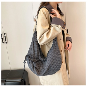 Macro detail of the grey checkered fabric texture and drawstring side of this crossbody bag
