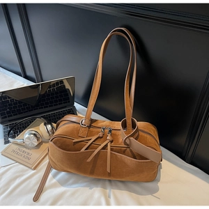 Macro shot of caramel suede bowling bag showing matte texture and dual zipper detail