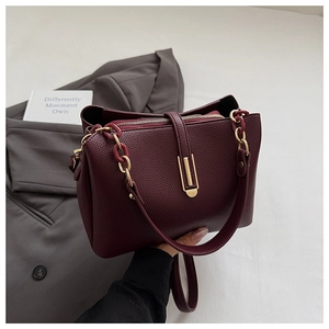 Detail of burgundy pebbled leather handbag with gold hardware and multi-compartment interior
