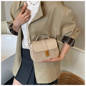 Detail of beige minimalist square bag with gold twist lock on trench coat outfit