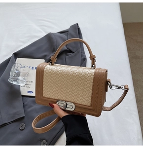 Detail of woven texture panel and brown leather trim on a stylish small square crossbody bag