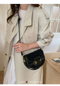 Bolso de montura negro con costuras blancas y hebillas doradas puesto con abrigo