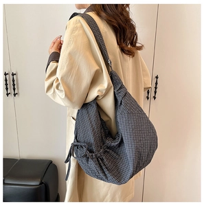Detail of grey checkered dumpling bag with drawstring bow and textured fabric surface