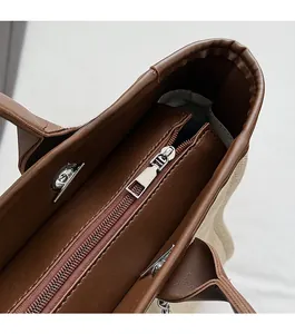 Detailed shot of smooth metal zipper and leather trim on a canvas tote bag
