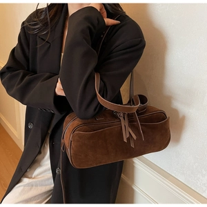 Detail of dark brown suede shoulder bag with long handles and tassel accessory