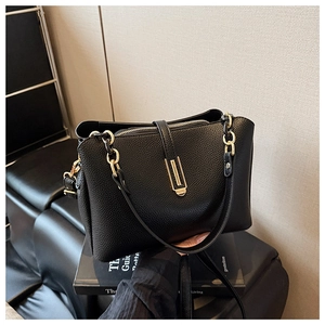 Detail of black lychee grain leather handbag with elegant gold metal clasp and chain links
