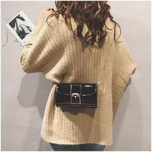Détail du sac carré en cuir verni noir brillant avec boucle dorée et bandoulière chaîne