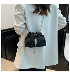 Detail of denim bucket bag showing quilted texture, silver chain and pearl drawstring charms