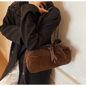 Detailed texture of brown matte suede shoulder bag with elegant leather tassel zipper