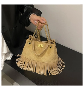 Detail of beige suede crossbody bag with long tassels and gold chain lock strap