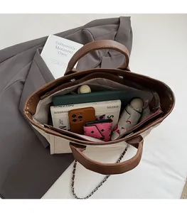 Spacious beige canvas and leather tote interior holding phone, wallet, and umbrella