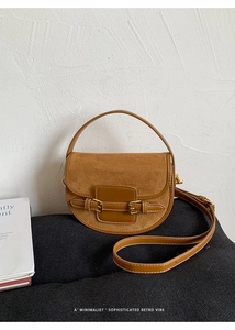 Detail of brown saddle bag showing suede and smooth leather texture with gold buckles