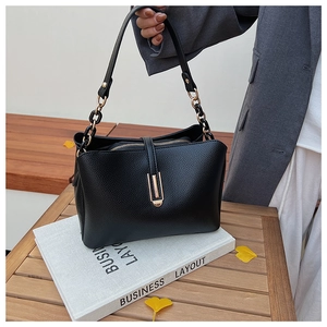 Close-up of black lychee grain PU leather bag with gold hardware and chain handle detail