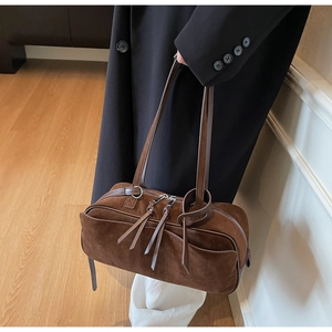 Close-up of matte brown suede bowling bag with dual long handles and vintage zip detail