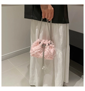 Detail of pink denim bucket bag featuring frayed edges, silver chain and pearl drawstrings
