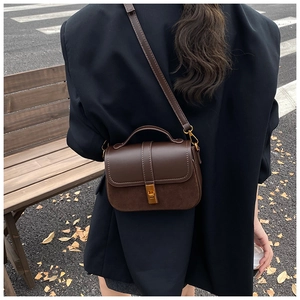 Detail of dark brown crossbody bag with mixed leather and suede textures on city street