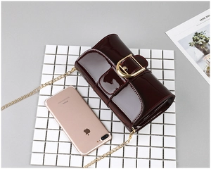 Détail du sac en cuir verni bordeaux avec boucle en métal doré et bandoulière