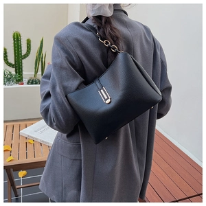 Detail of black litchi leather shoulder bag with gold U-shaped buckle and chain strap