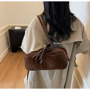 Detail of dark brown suede shoulder bag showing texture and leather drawstring detail