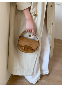 Detail of a brown retro suede saddle bag with leather straps and gold buckle