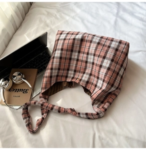Détail d'un sac cabas à carreaux roses avec bouton doré et bandoulière large nouée