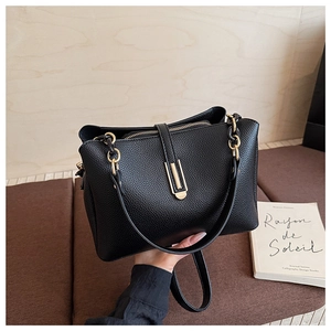 Detail of black lychee grain leather handbag with elegant golden metal lock and chain