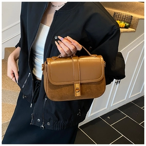 Detail view of brown leather patchwork bag with gold twist lock and top handle grip