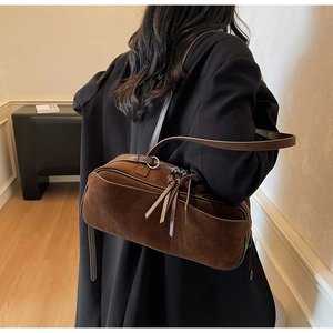 Detail of dark brown suede shoulder bag with long leather strap and tassel zipper pull