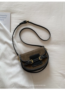 Detail of retro saddle bag with brown suede flap, black leather and white stitching