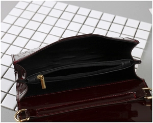 Détails de l'intérieur du sac à main en cuir verni bordeaux avec fermeture éclair dorée