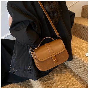 Detail of vintage brown textured leather crossbody bag with metal twist lock and shoulder strap
