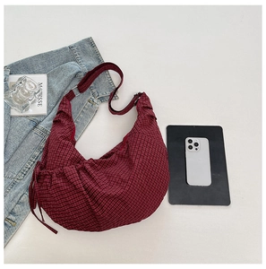 Macro detail of wine red plaid crescent bag featuring adjustable strap and drawstring texture