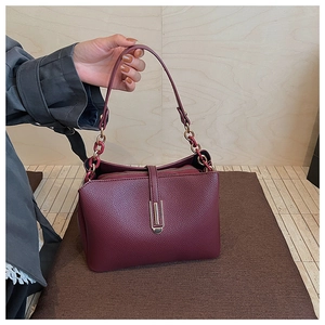 Close-up of wine red litchi grain leather bag with elegant golden chain strap detail