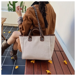 Outdoor view of off-white canvas tote bag with brown trim on a wooden bench